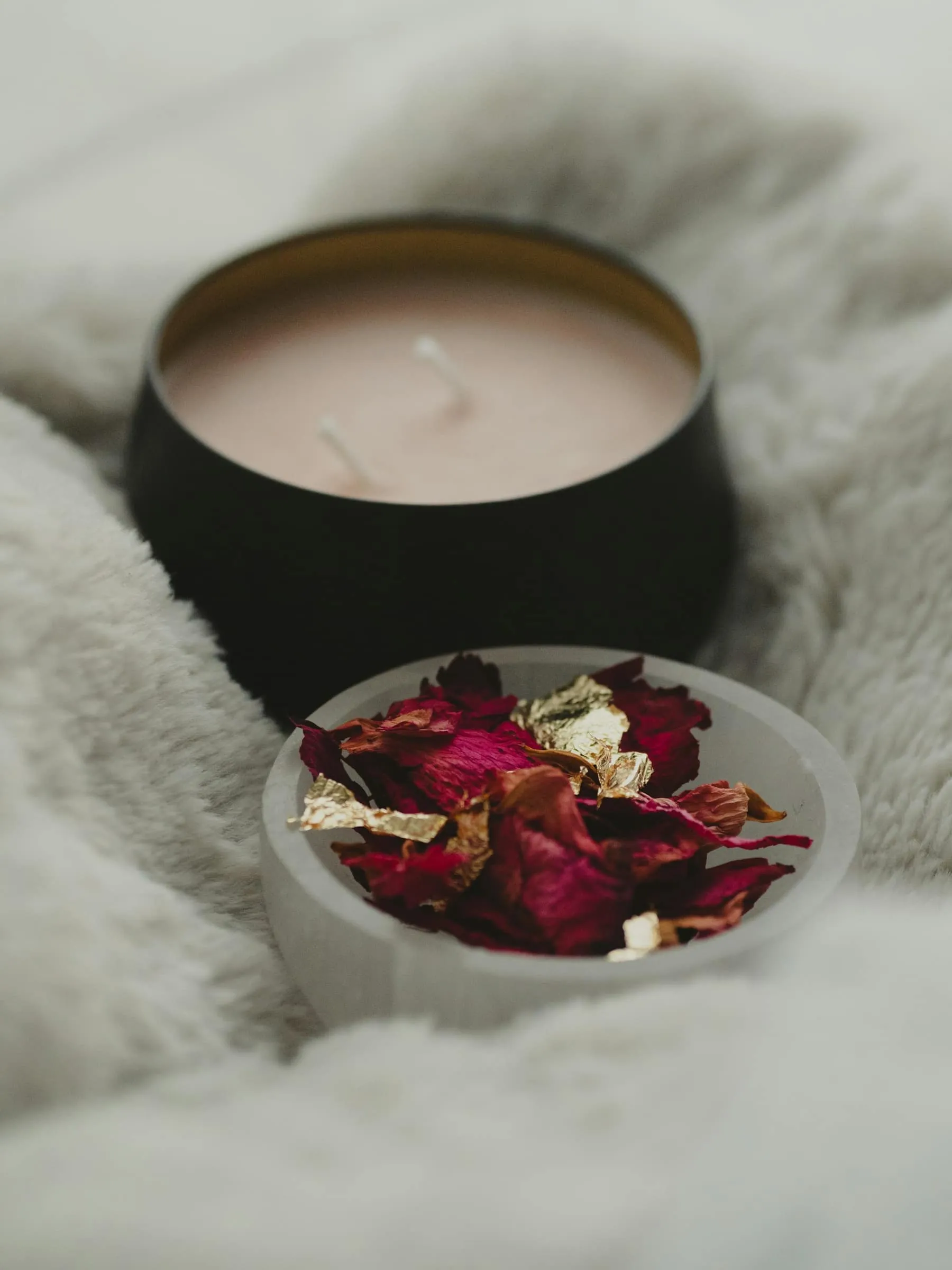 Bougie allumée et coupelle de pétales de rose sur un plaid